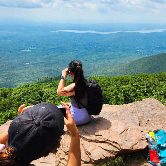 Two people taking photos of a scenic view from a high vantage point.