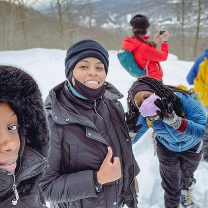 Group of people in winter clothing on a snowy landscape with mountains in the background.
