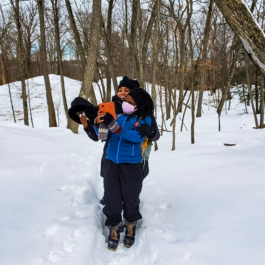 2 hikers taking selfies in a snowy forest