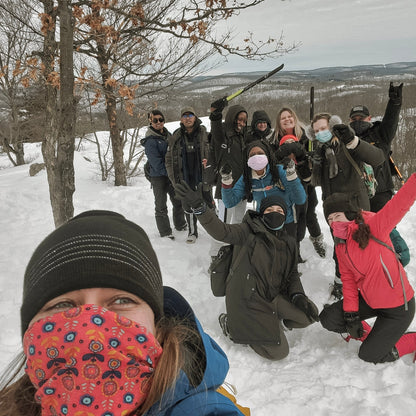 Group of people posing in the snow with winter clothing and masks.