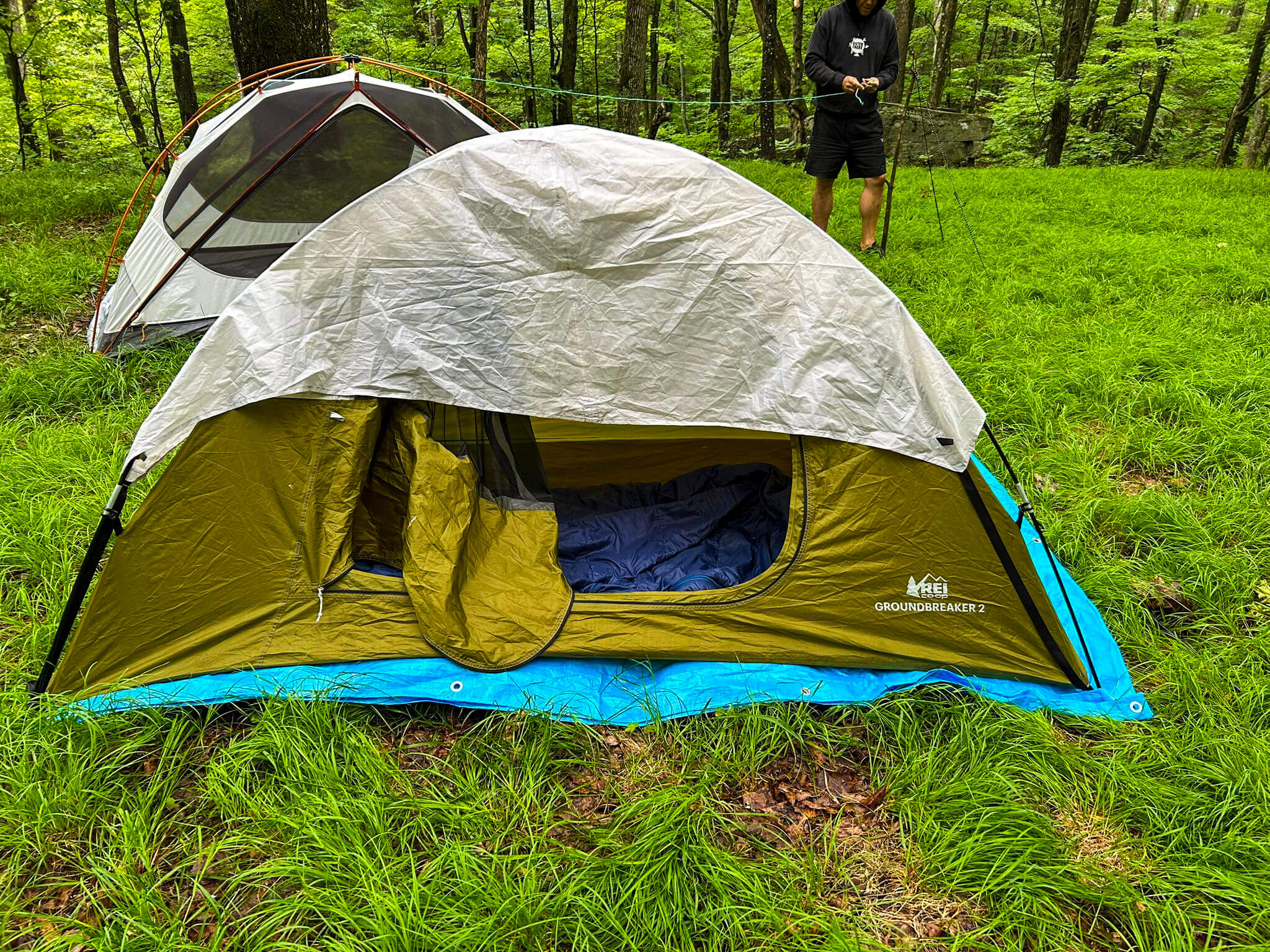 Two camping tents set up in a grassy area with a person in the background.