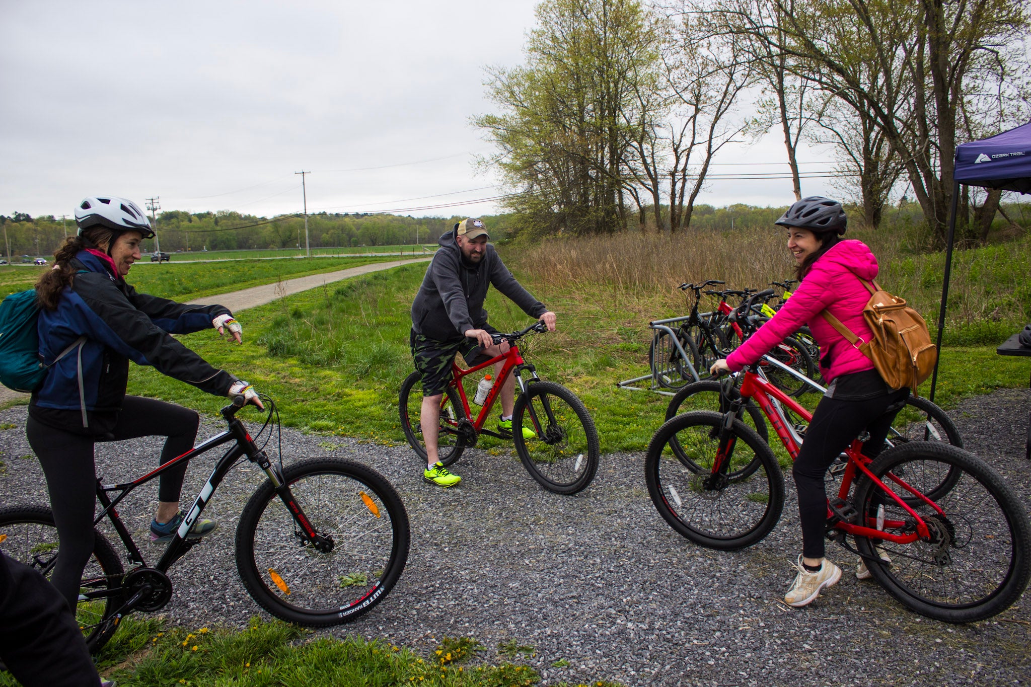 Group of people with bicycles on a gravel path with trees and grass in the background