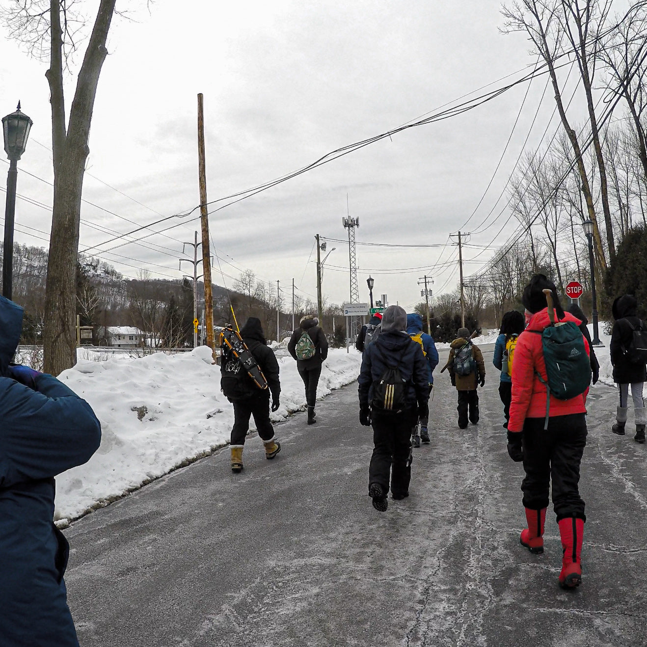 People walking on a snowy road with a cloudy sky